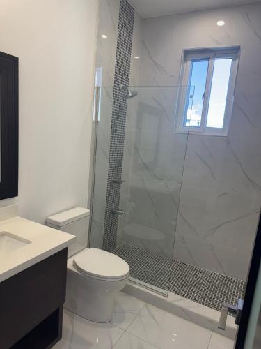 a bathroom with a toilet and a glass shower at City Abode Kingston Jamaica in Kingston