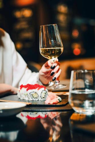 a person holding a glass of wine and a plate of food at Skopje Marriott Hotel in Skopje