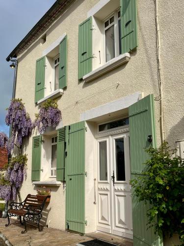 a building with green shutters and a door and a bench at Le Charme du Perigord - chambre & table d'hotes in Saint-Sulpice-dʼExcideuil