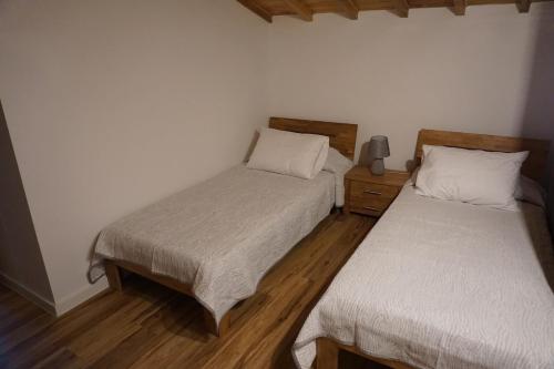 a bedroom with two beds and a wooden floor at Casa Mamã e Papá in Mosteiros