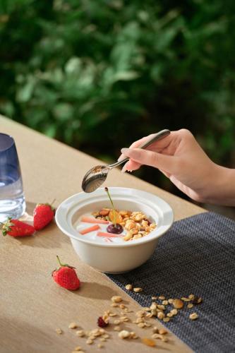 a person eating a bowl of cereal with a spoon at The Westin Resort & Spa Cam Ranh in Cam Ranh