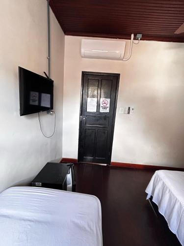 a room with a bed and a door with a tv at Pousada Matriz in Paraty