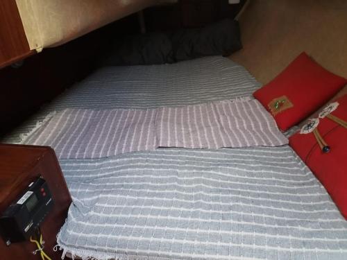 a bed with a blue mattress and a red pillow at 2-cottage yacht with 2 showers in Datca
