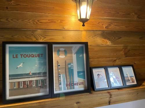 a shelf with three framed pictures on a wooden wall at Magnifique Tiny House avec jacuzzi privatif proche du Touquet Paris plage in Étaples