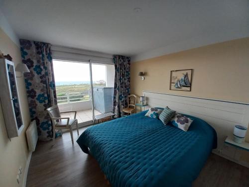 une chambre avec un lit bleu et une grande fenêtre dans l'établissement Appartement - Résidence l'Estran - Sables d'Olonne, à Les Sables-dʼOlonne