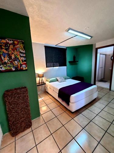 a bedroom with a bed and a green wall at Hostal La Paz & Love Guadalajara in Guadalajara