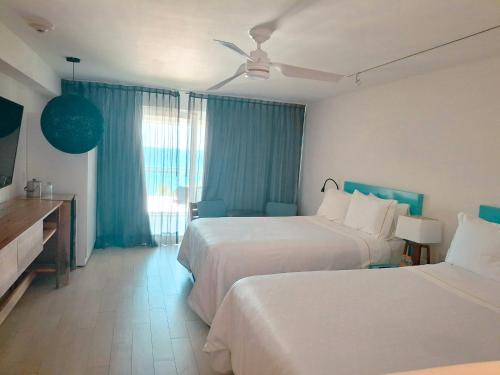 a hotel room with two beds and blue curtains at Fiesta Americana Cozumel All Inclusive in Cozumel