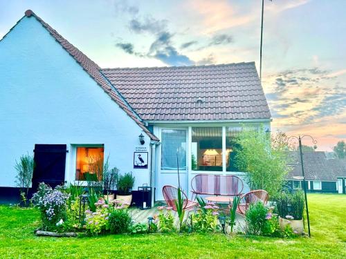 une maison blanche avec une table et des chaises dans la cour dans l'établissement Le Cocoon de la Héronnière, à Houlle