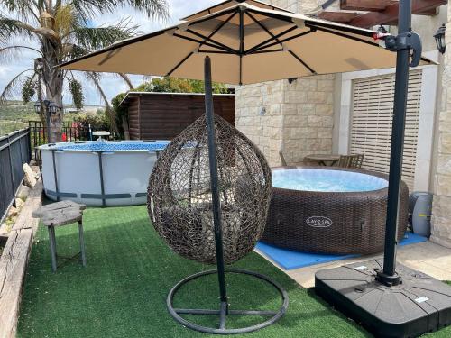 an umbrella next to a pool with a swing at צימרימון in Bet Rimmon