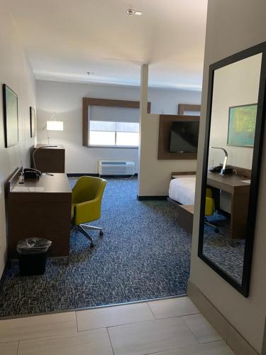 a hotel room with a bed and a desk and a mirror at Comfort Inn & Suites Near Lake Guntersville in Scottsboro