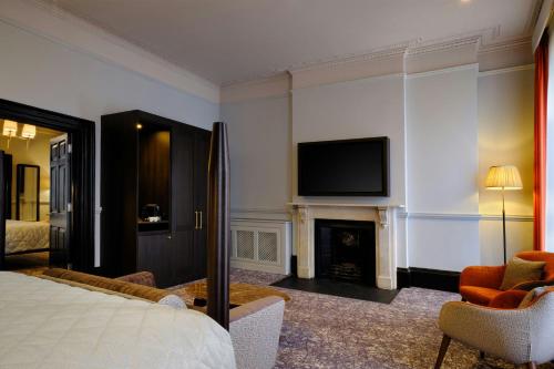 a bedroom with a bed and a fireplace and a television at Abbey Hotel Bath, a Tribute Portfolio Hotel in Bath