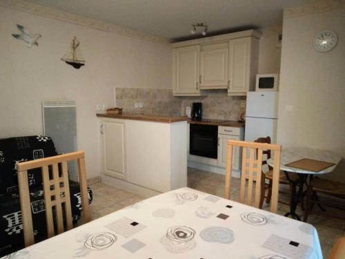 une cuisine avec des armoires blanches et une table et des chaises dans l'établissement Résidence Villa Helios - SAINT MARC SUR MER 2 pièces centre-ville MAE-6281, à Géraud