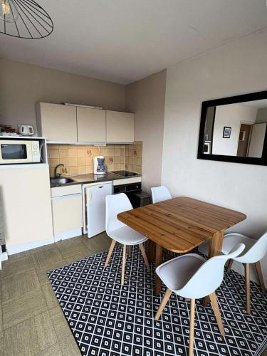 - une cuisine avec une table en bois et des chaises blanches dans l'établissement Résidence Le Renaissance - Pornichet - Studio Place du Marché MAE-6571, à Pornichet