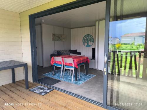 eine abgeschirmte Veranda mit einem roten Tisch und Stühlen in der Unterkunft cottage Landes entre terre et ocean in Saubrigues