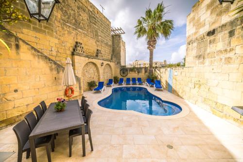 een terras met een tafel en stoelen en een zwembad bij Caqsi Farmhouse in Kerċem