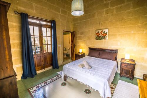 een slaapkamer met een groot bed en een raam bij Caqsi Farmhouse in Kerċem