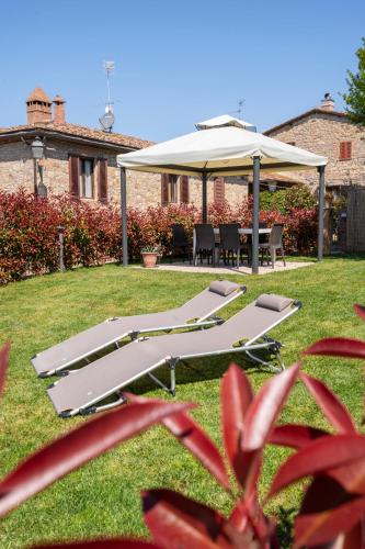a group of lounge chairs and an umbrella in a yard at Casa Nataly Chianti - Jeky Stay in Castelnuovo Berardenga