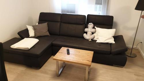 Un sofá negro en una sala de estar con una mesa. en Ferienhaus Andy Kellenhusen - 6 Personen 3 Schlafzimmer 4, en Kellenhusen