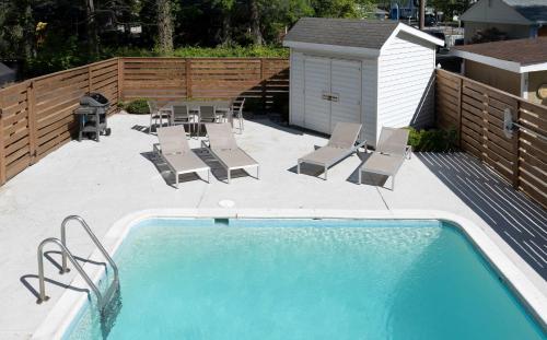 a swimming pool with chairs and a table and a fence at The VIBE House with POOL in Virginia Beach