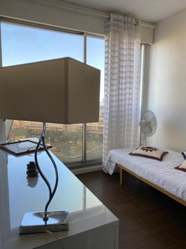 une chambre avec un lit et un bureau avec une lampe dans l'établissement T2 Spacieux à Carnon, à Mauguio