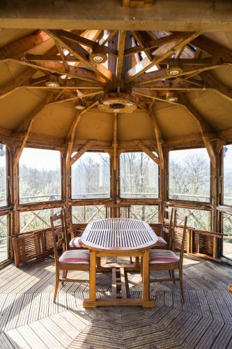 une table et des chaises dans une pièce avec des fenêtres dans l'établissement VillaNona, à Saint Remy sur Orne