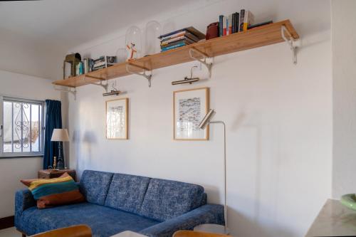 a living room with a blue couch and a shelf at 2-bedroom house w garden in heart of Ferragudo village in Ferragudo