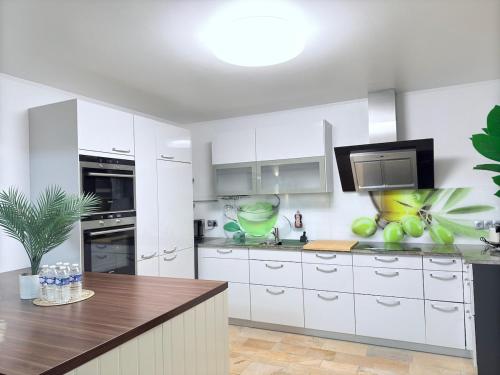 a white kitchen with white cabinets and a television at Beautiful house with garden, game, gym, terrace&parking in Strassen