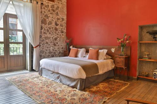een slaapkamer met een bed en een rode muur bij CASA SAUTO Historic Fam Suite 1 block from Zocalo in Mexico-Stad