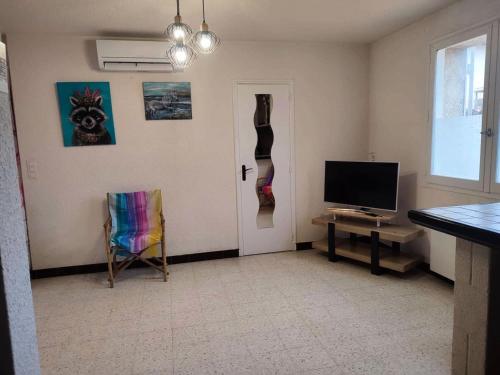Cette chambre dispose d'une porte, d'une télévision et d'une chaise. dans l'établissement Résidence Ccamt38-aigues Mortes - Appart coeur Camargue Aigues mortes T2 MAE-5361, à Aigues-Mortes