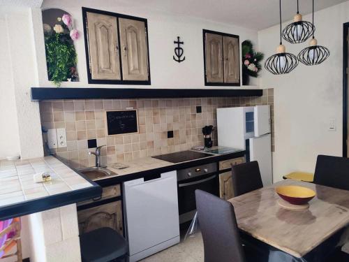 une cuisine avec un évier et une table avec des chaises dans l'établissement Résidence Ccamt38-aigues Mortes - Appart coeur Camargue Aigues mortes T2 MAE-5361, à Aigues-Mortes