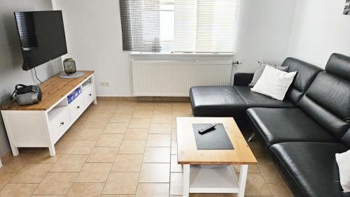 Una sala de estar con un sofá de cuero negro y un televisor. en Ferienhaus Angela Kellenhusen - 6 Personen 3 Schlafzimmer 4, en Kellenhusen