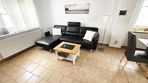Una sala de estar con un sofá negro y una mesa. en Ferienhaus Angela Kellenhusen - 6 Personen 3 Schlafzimmer 4, en Kellenhusen