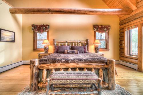 a bedroom with a wooden bed and two windows at Most Luxury 7000 Sq ft Log Estate with Pool Hot Tub Sauna in Wilmington