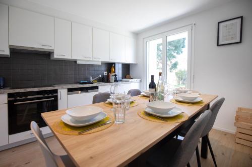 a kitchen with a wooden table with chairs and a dining room at Superbe appartement 3,5 pièces, parking gratuit in Farvagny-le-Grand