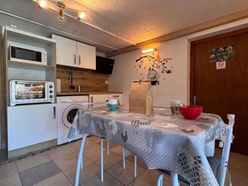 une cuisine avec une table et une machine à laver dans l'établissement Les Iris, appartement modeste en sous-sol, à Saint-Valery-sur-Somme