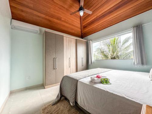 a bedroom with a bed with a ceiling fan and a window at Casa Superior Pedro Tavares in Búzios