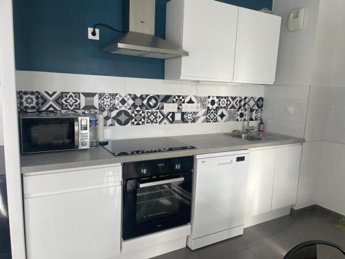 a kitchen with white cabinets and a stove and microwave at Appartement T3 Curistes in Dax