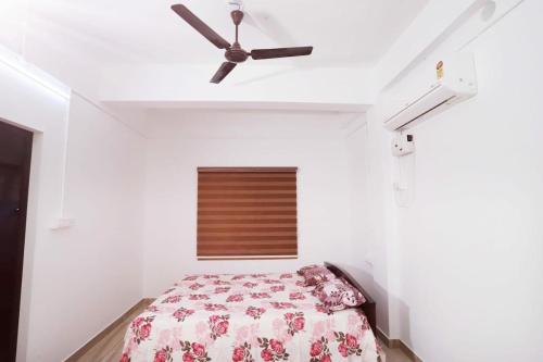 a bedroom with a bed and a ceiling fan at bethel apartments teekoy in Erāttupetta