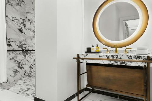 a bathroom with a round mirror and a sink at The Gunter Hotel San Antonio Riverwalk in San Antonio
