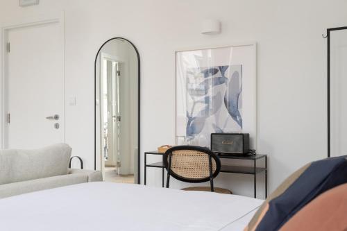 a bedroom with a bed and a chair and a mirror at Lapa Diplomatic Suites & Flats by Feel Lisboa in Lisbon