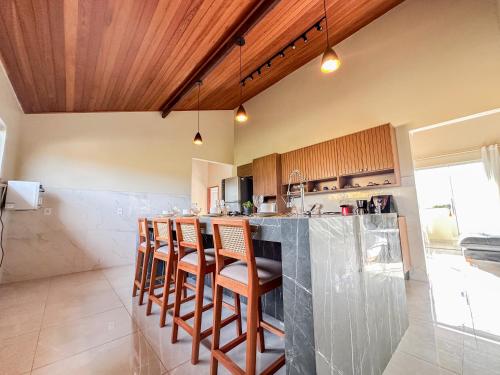 a kitchen with a bar with stools in it at Casa Superior Pedro Tavares in Búzios
