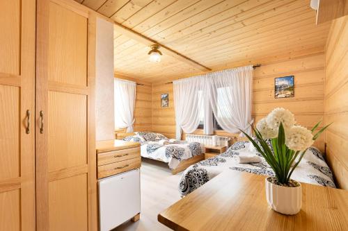 a bedroom with two beds and a table with a vase of flowers at Willa Emilia in Zakopane