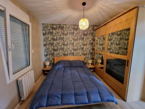 - une chambre avec un grand lit bleu dans l'établissement Le jardin de Chouchat, à Gavray