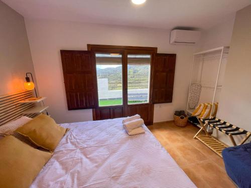 a bedroom with a large bed and a window at El Balcón de Ohanes R&R in Ohanes