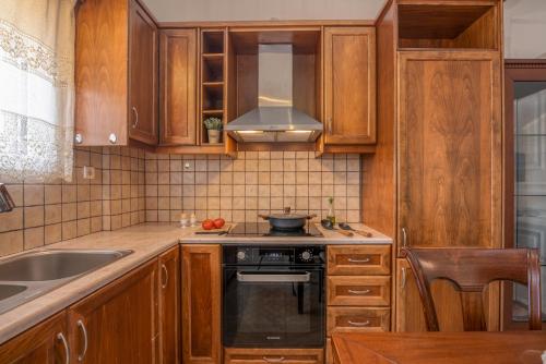 a kitchen with wooden cabinets and a stove top oven at Achilleas Deluxe House-Jacuzzi - BBQ in Kotsianá