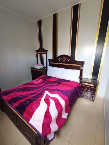a bedroom with a large bed with a red and white blanket at Maison Jad in Ifrane
