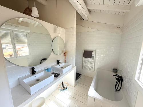 a white bathroom with two sinks and a mirror at Domaine la Clausade in Mauguio