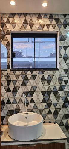 a bathroom with a white sink and a window at PAX Lofts e Suítes in Penha
