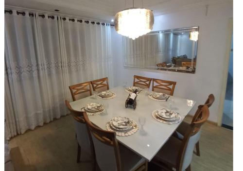 グアルジャにあるApto Aconchegante Piscina 2 Vagasのダイニングルーム(白いテーブルクロスと椅子付)