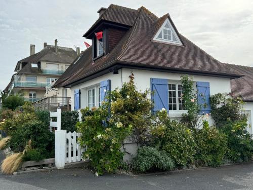 une maison blanche avec des fenêtres bleues et une clôture blanche dans l'établissement Maison de vacances VUE MER ET CANAL, à Ouistreham